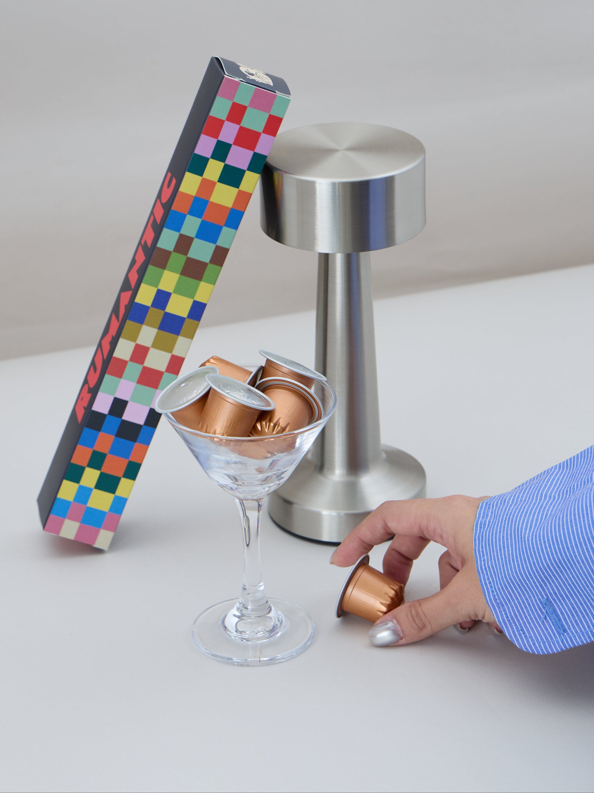 Multicolored checkered box with a silver stand and glass on a white surface.